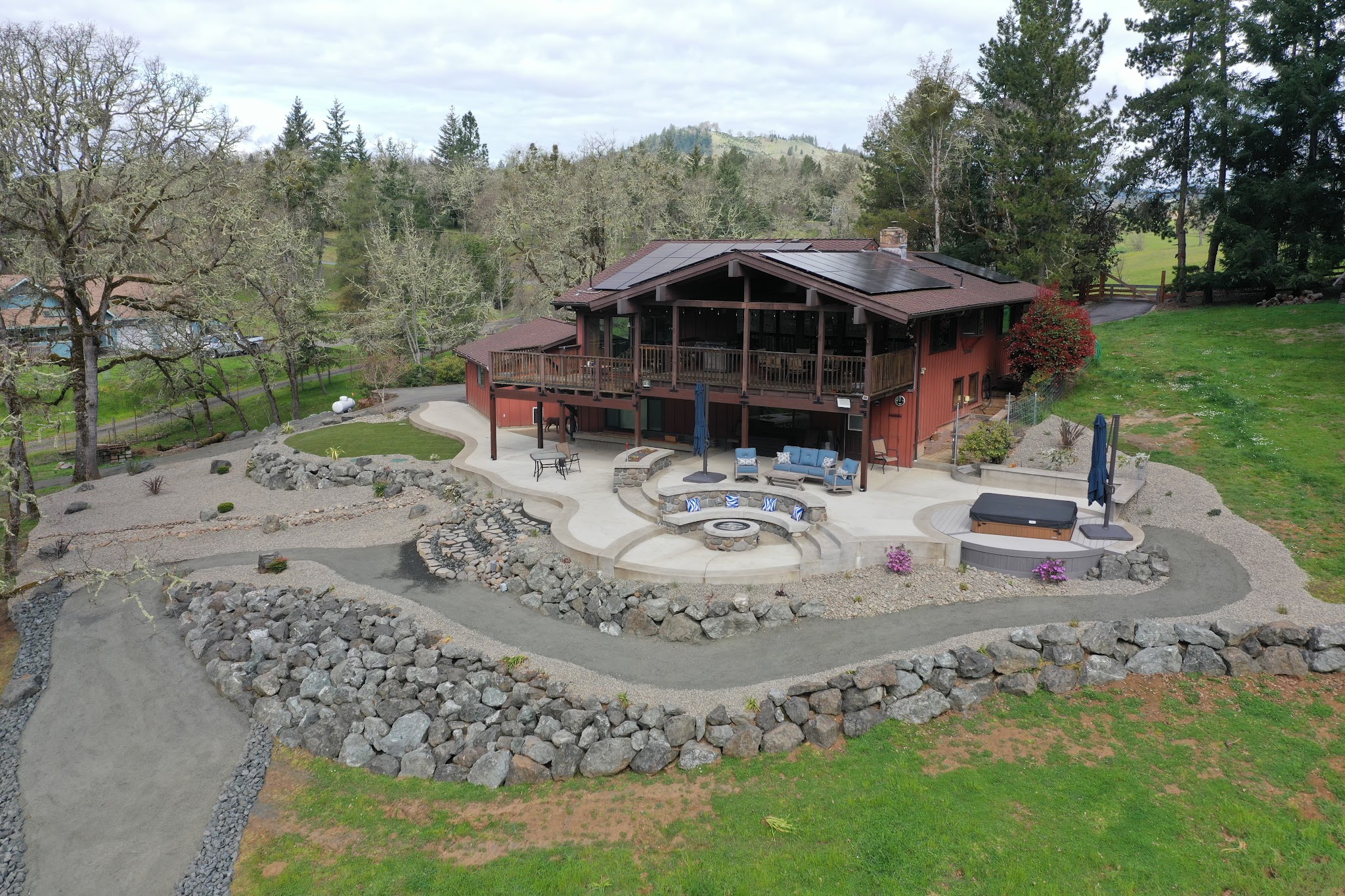 Aerial view of a finished backyard landscaping project with stone patio, fire pit and hot tub